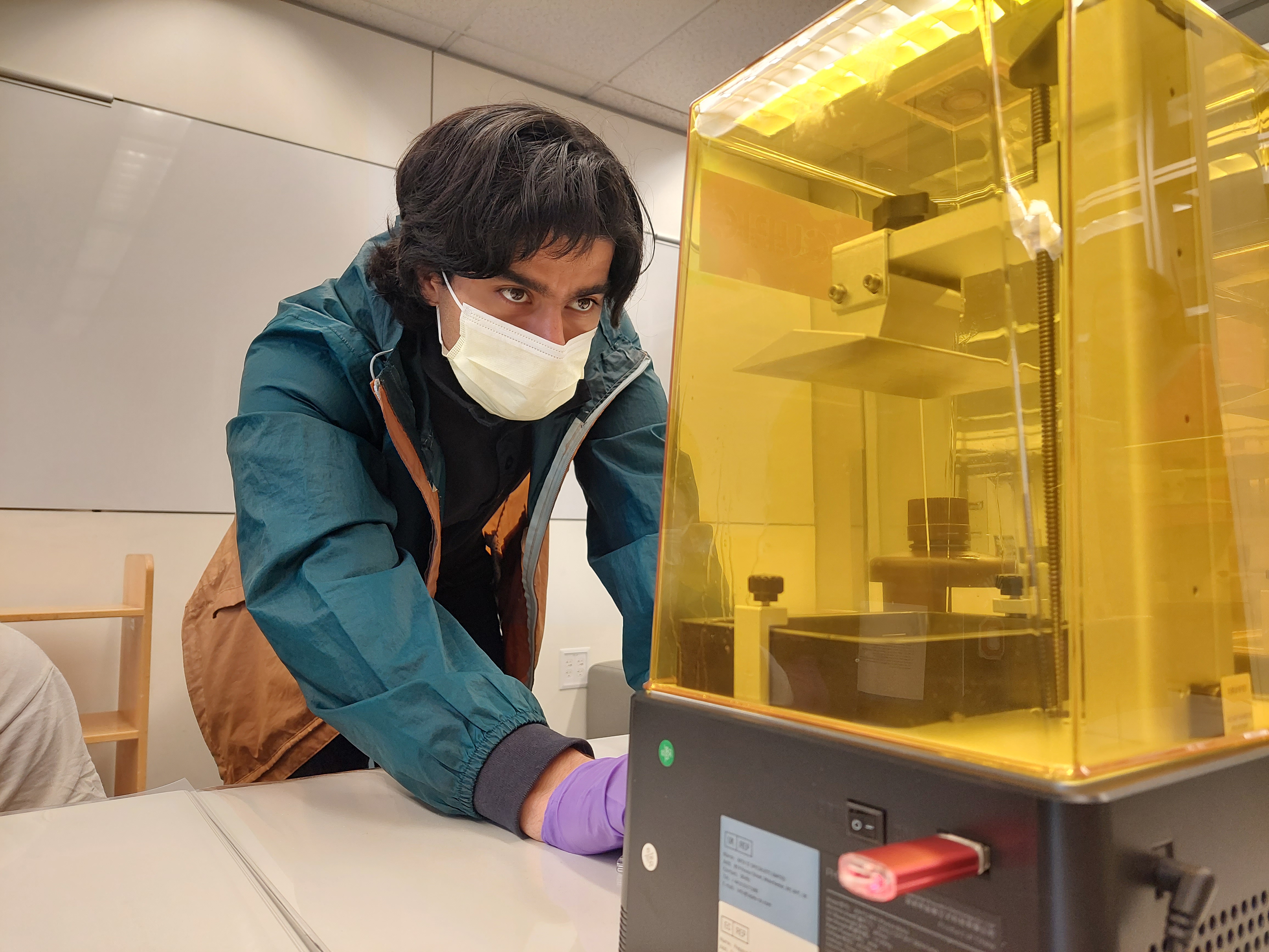 A man looks at a 3D resin printer