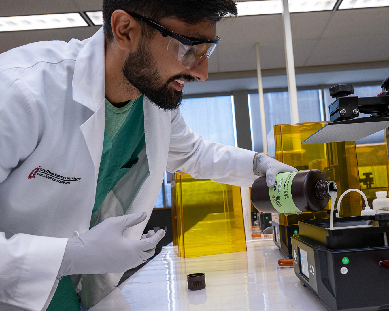 Medical student pooring resin into a 3D printer.