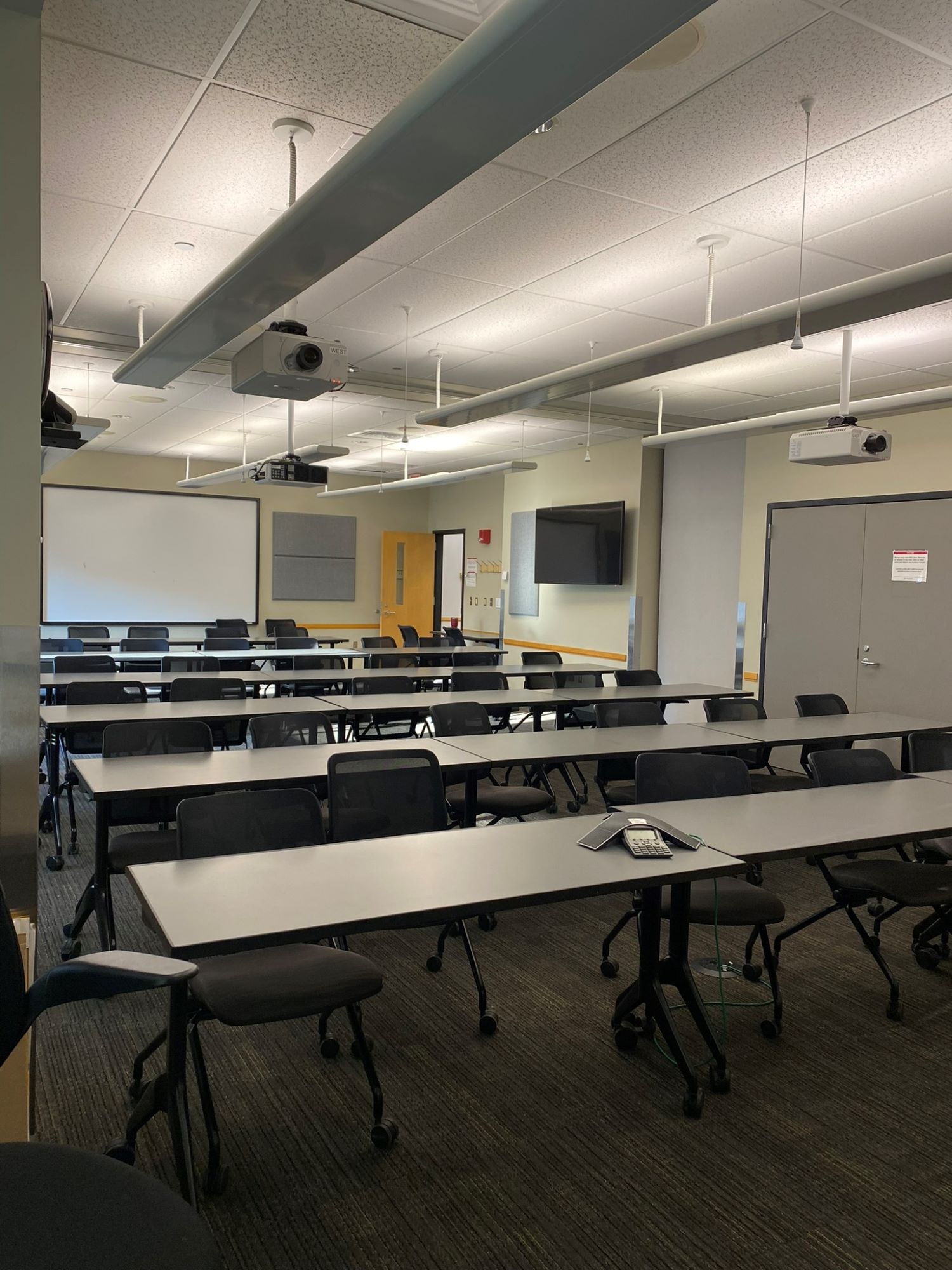 Interior of the Tech-Equipped Classroom featuring several rows of desks and a large projection screen on one wall.
