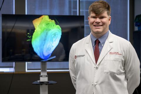 Dr. Blair Suter standing in front of 3D CT scan of heart on a screen