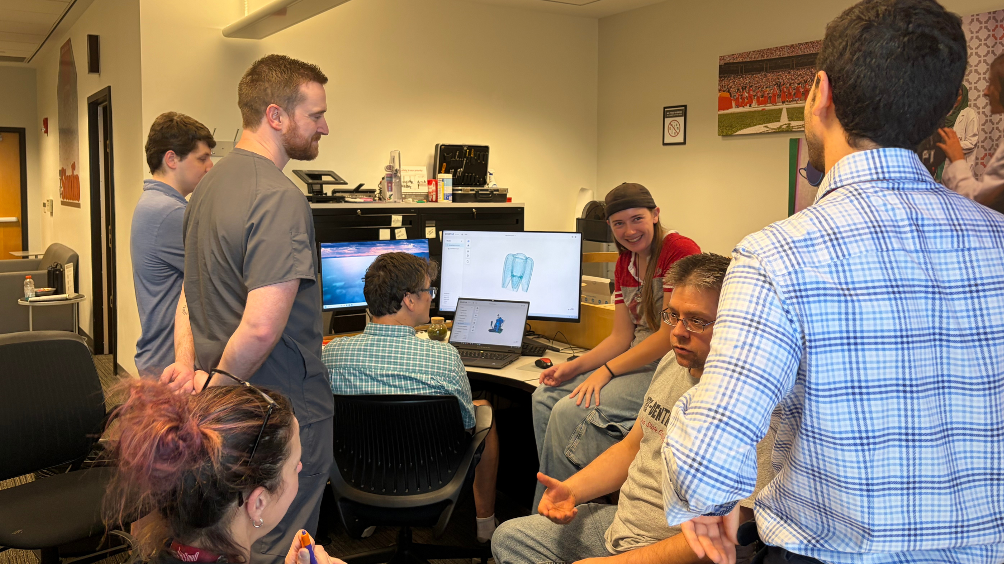 Group talking around computer that displays a 3D model.